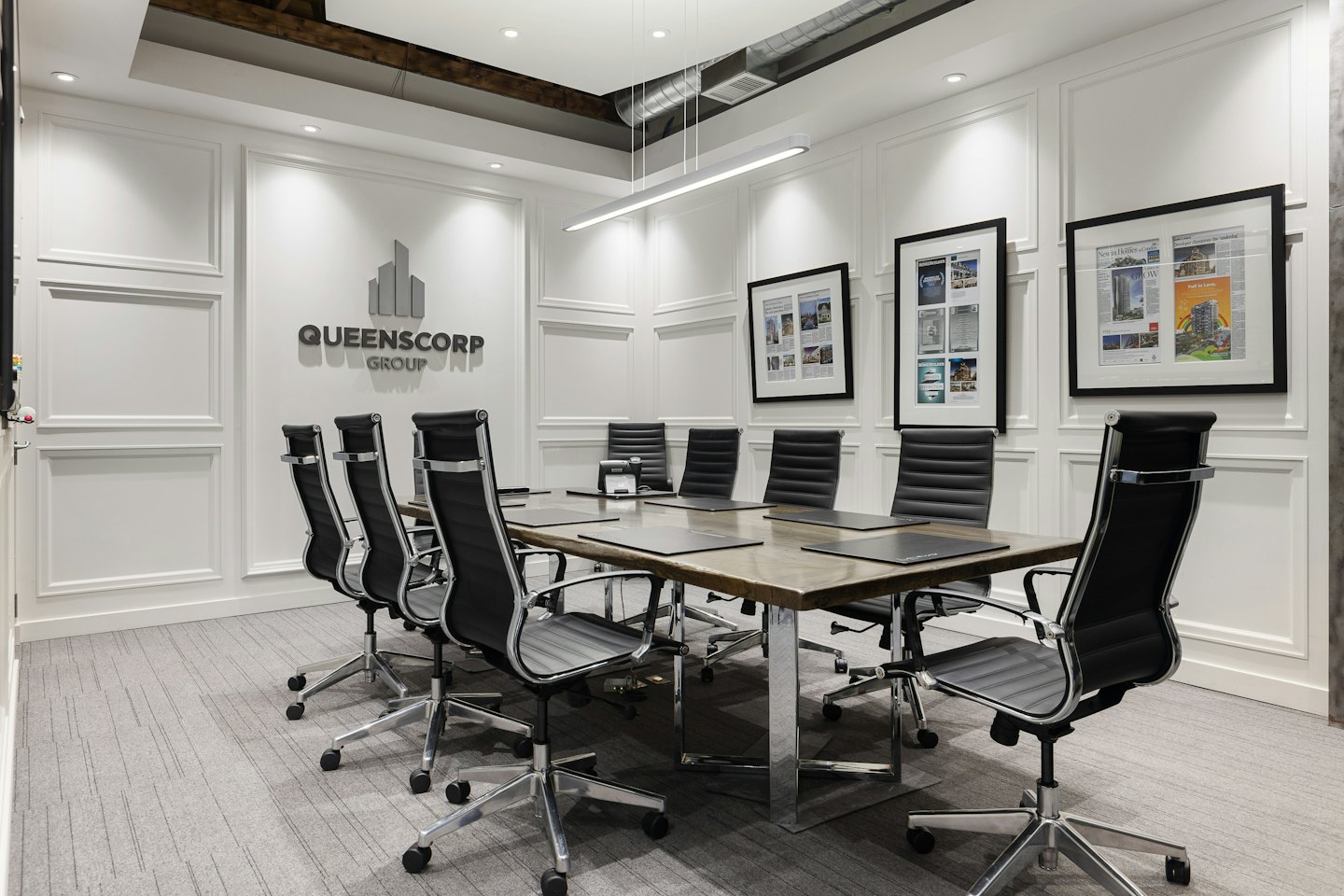 Conference room with long table and Queenscorp Group logo.
